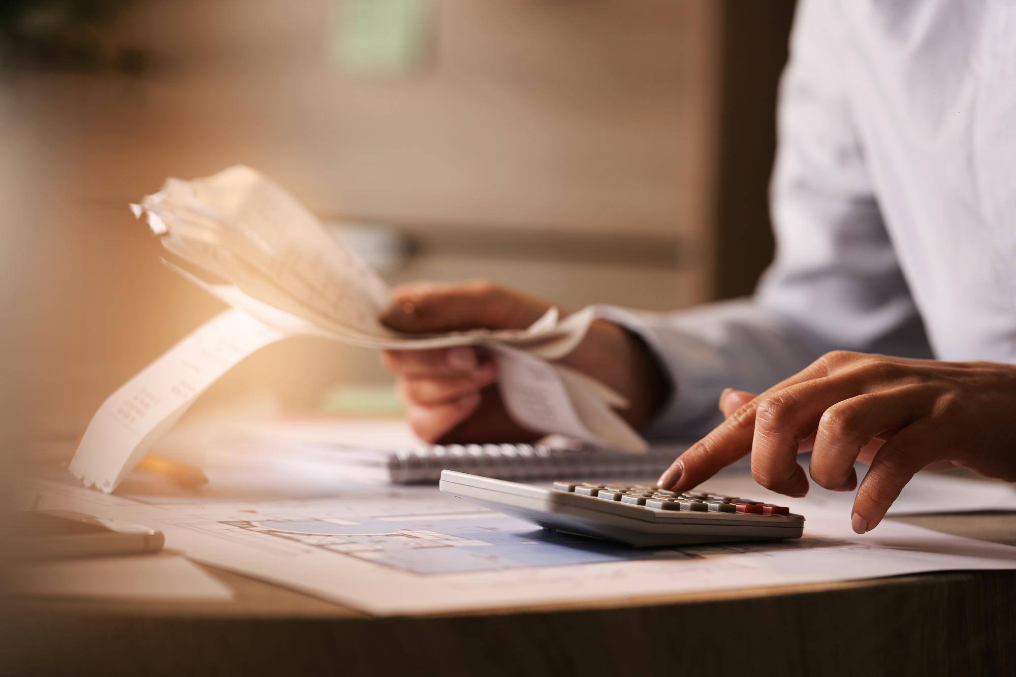 closeup-economist-using-calculator-while-going-through-bills-taxes-office